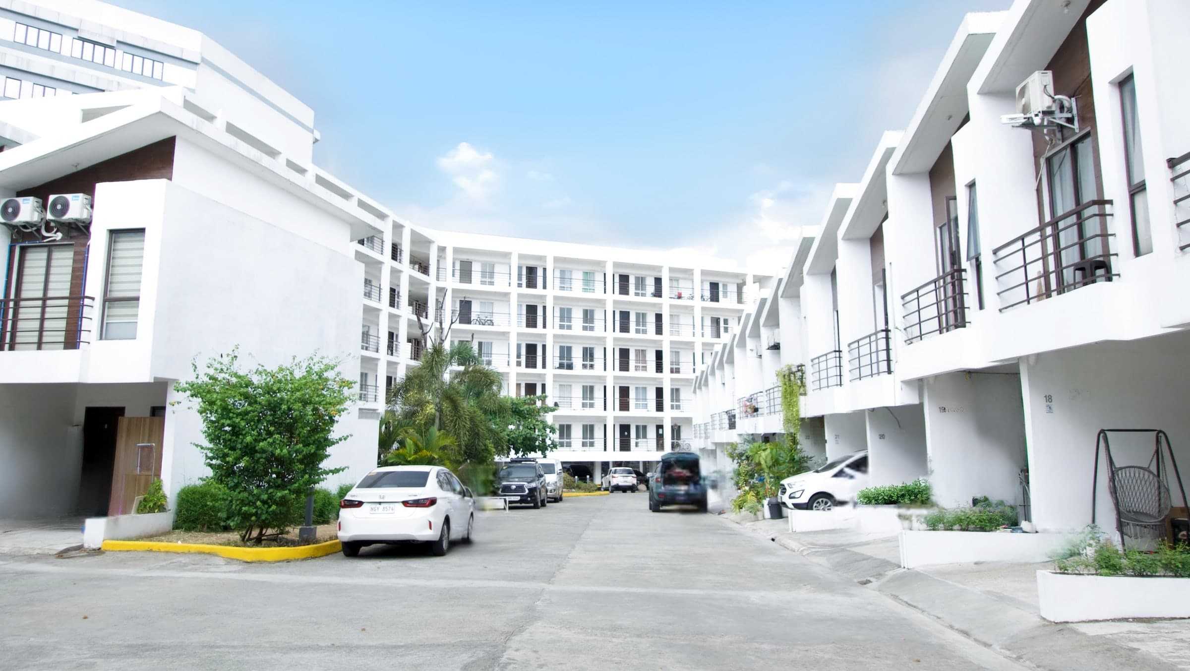 Courtyard at Eleve Camarin in Caloocan, townhouses along one side and the mid-rise condominium block beyond
